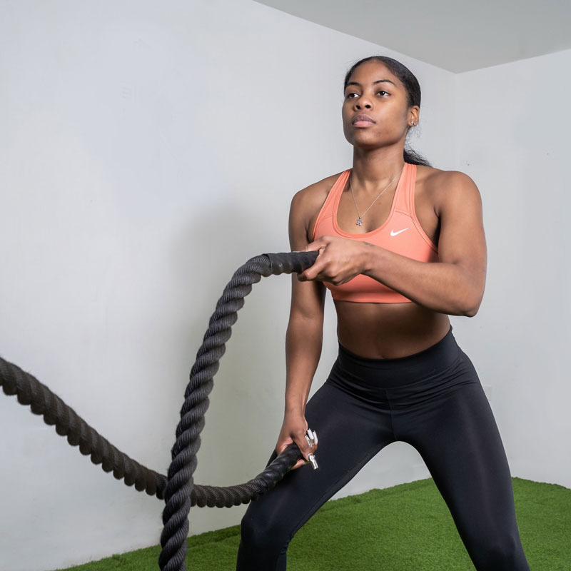 The coach performs a battle ropes exercise.